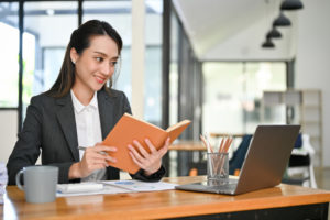Asian businesswoman research information in a book while working at her desk in the office. Free CEUs for Counselors